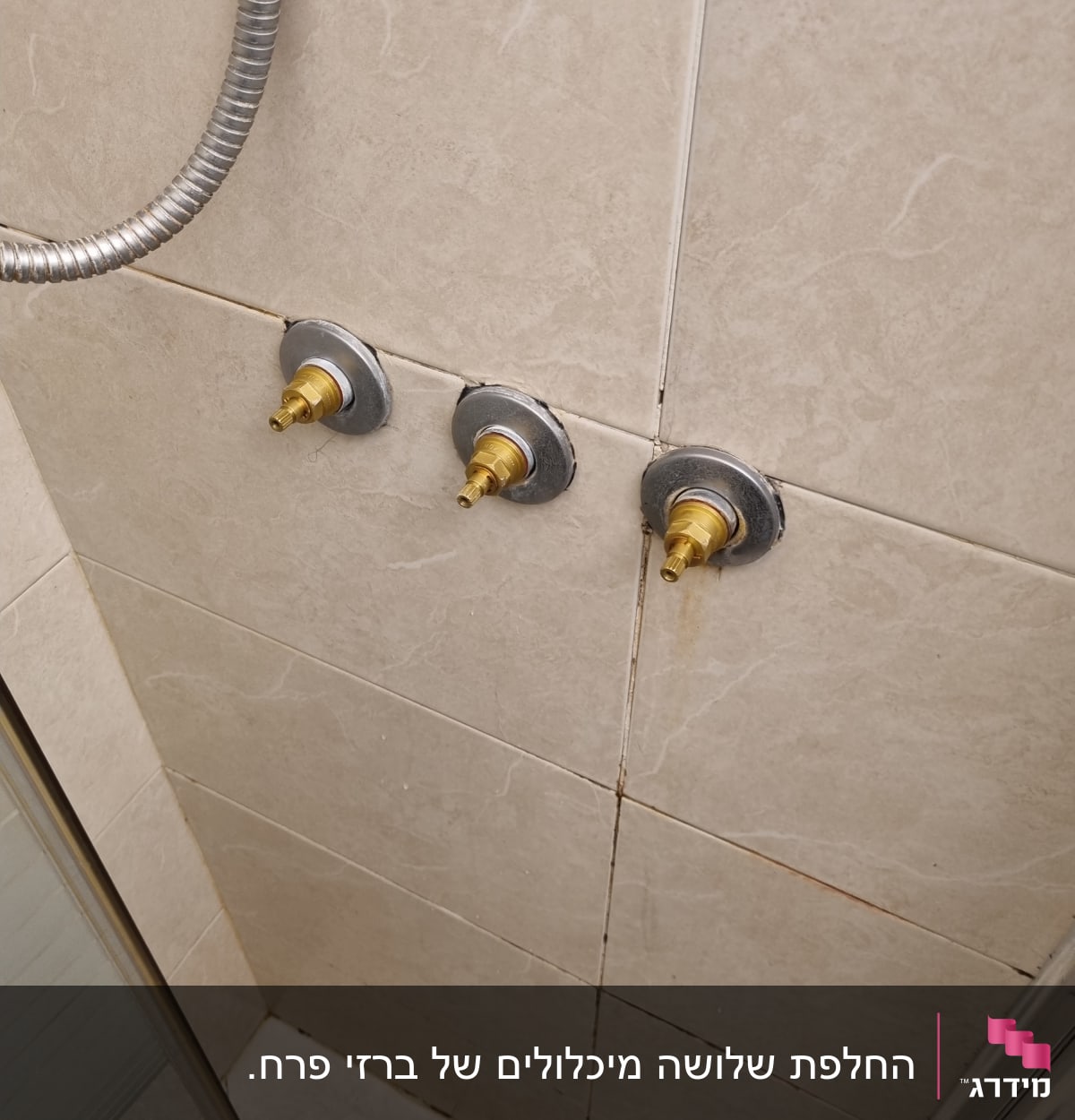 ברזי מים חשופים על קיר אריחים במקלחת